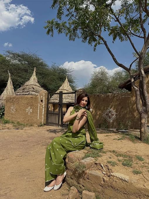 Model seated wearing an olive green Farshi salwar suit with matching dupatta