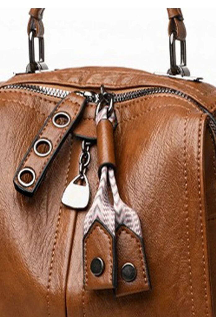 Close-up of brown handbag showing textured finish, zip fastening and metal details